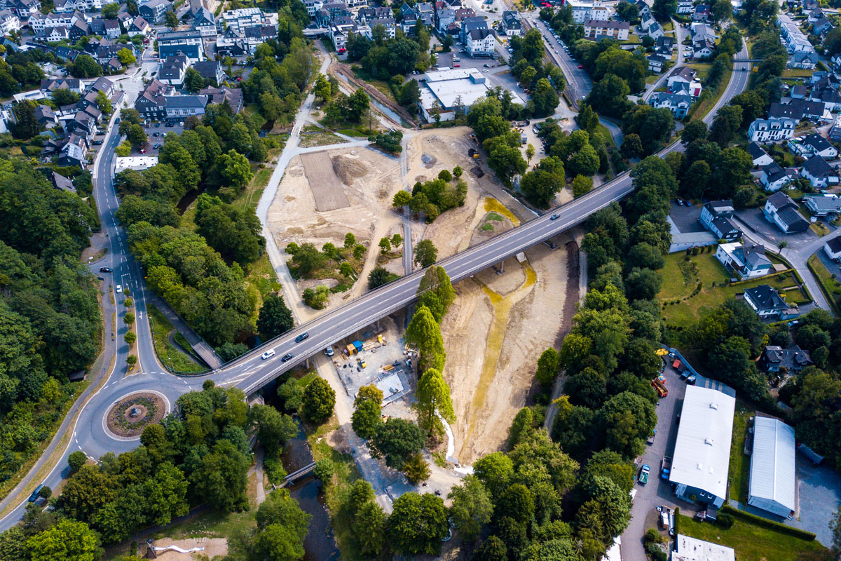 Die Baustelle des Wiehlparks Ende Juli 2022: Links unterhalb der Brücke ist die Bodenplatte fürs Seecafé zu sehen. Gut zu erkennen ist das Netz der Hauptwege sowie am oberen Rand der mit Wasser gefüllte Teil des Zulaufs in den See. Foto: Stadt Wiehl